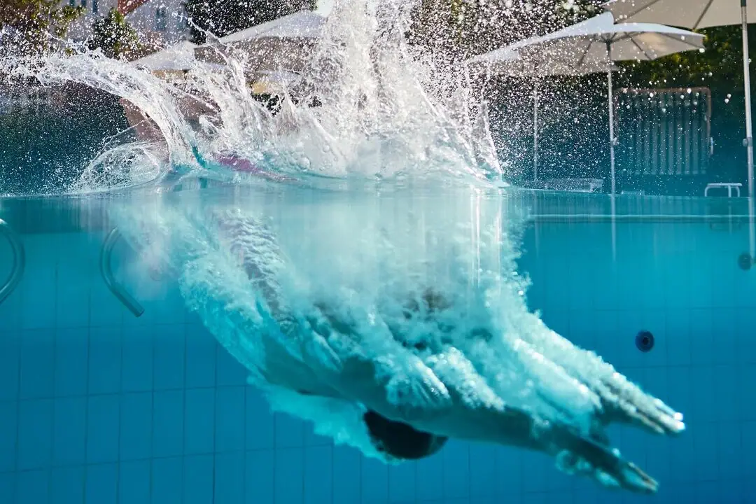 Persona che si tuffa in una piscina all'aperto.