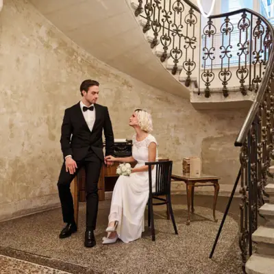 Un uomo e una donna seduti su una sedia in una stanza con scale.