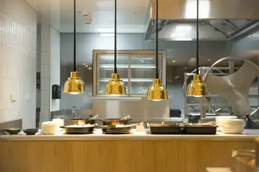 Cucina con pentole appese al soffitto e lavello a vista.
