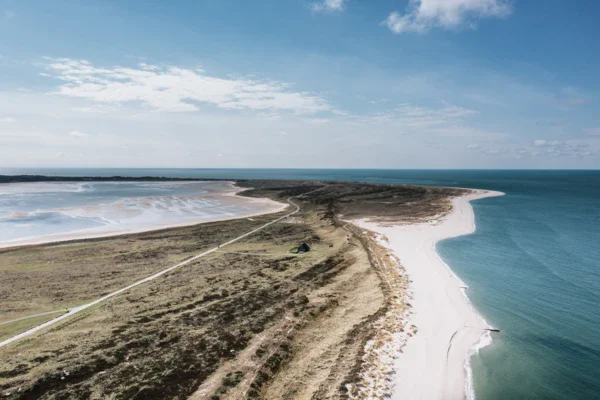 Spiaggia sabbiosa con acqua e cielo nuvoloso.