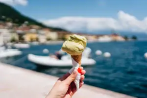 Eis Eine Hand hält ein Eis in einer Waffel mit einem Boot im Hintergrund.