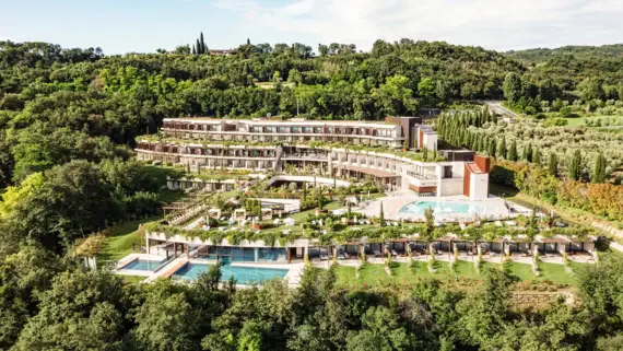 Vista aerea di un resort circondato da una vegetazione lussureggiante, alberi e aree erbose.