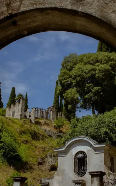 Un arco in pietra con un muro di pietra e alberi.