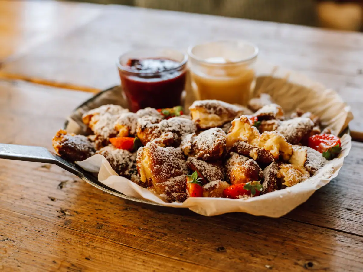 Kaiserschmarrn Piatto di cibo con due bicchieri di marmellata.