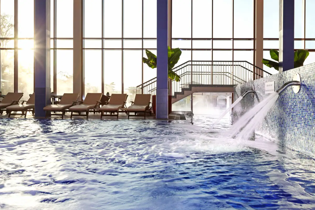 Ein Pool mit Schwallduschen und Liegestühlen im Hintergrund.