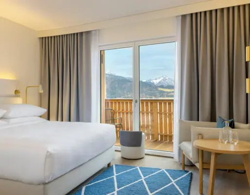 Hotelzimmer mit Bett, Teppich und Sessel.