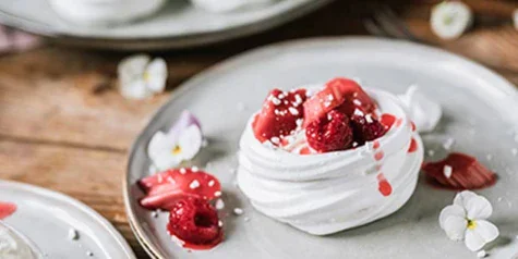 Piatto di dessert con gelato, frutta e crema su un tavolo.