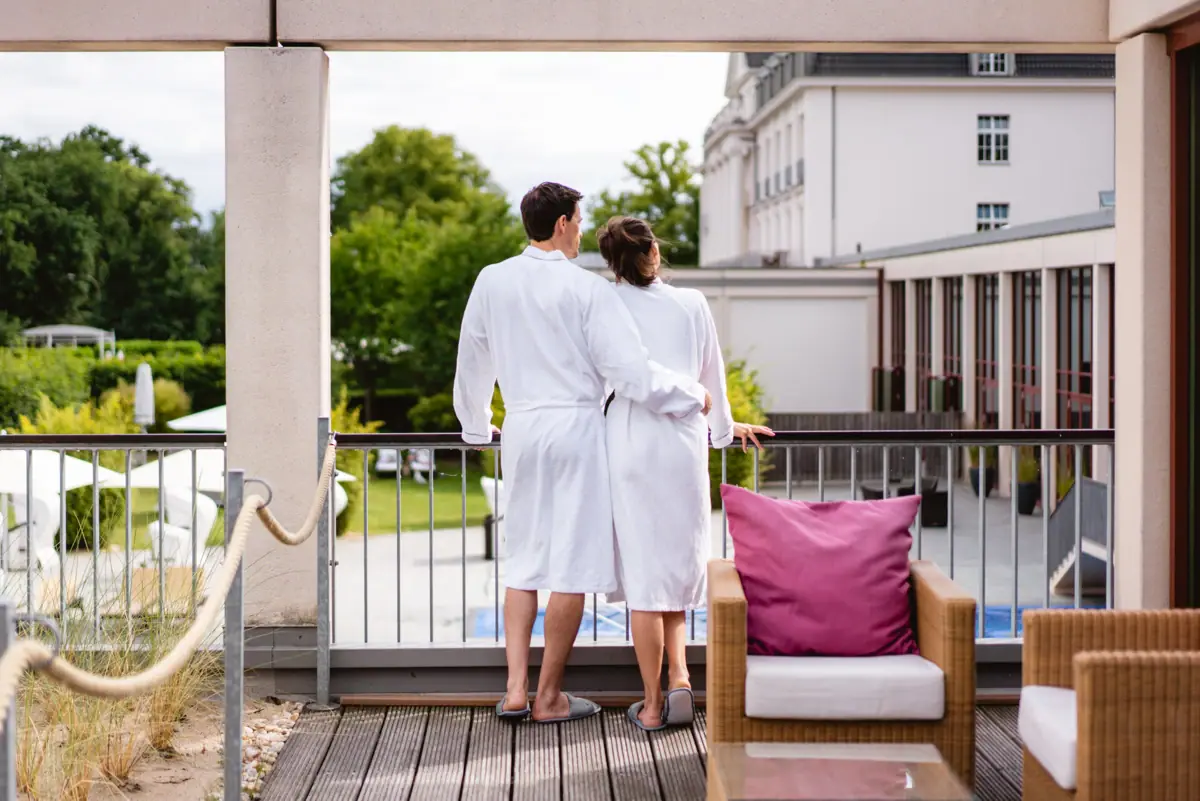 SPA-ROSA Travemünde Un uomo e una donna in accappatoi bianchi sono in piedi su un balcone.