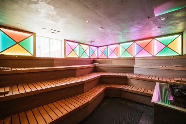 Eventsauna mit bunten Lichtern und Sitzbänken aus Holz.