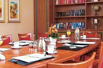 Meetingraum Ein Tisch mit einem Bücherregal und einer Vase mit Orangensaft.