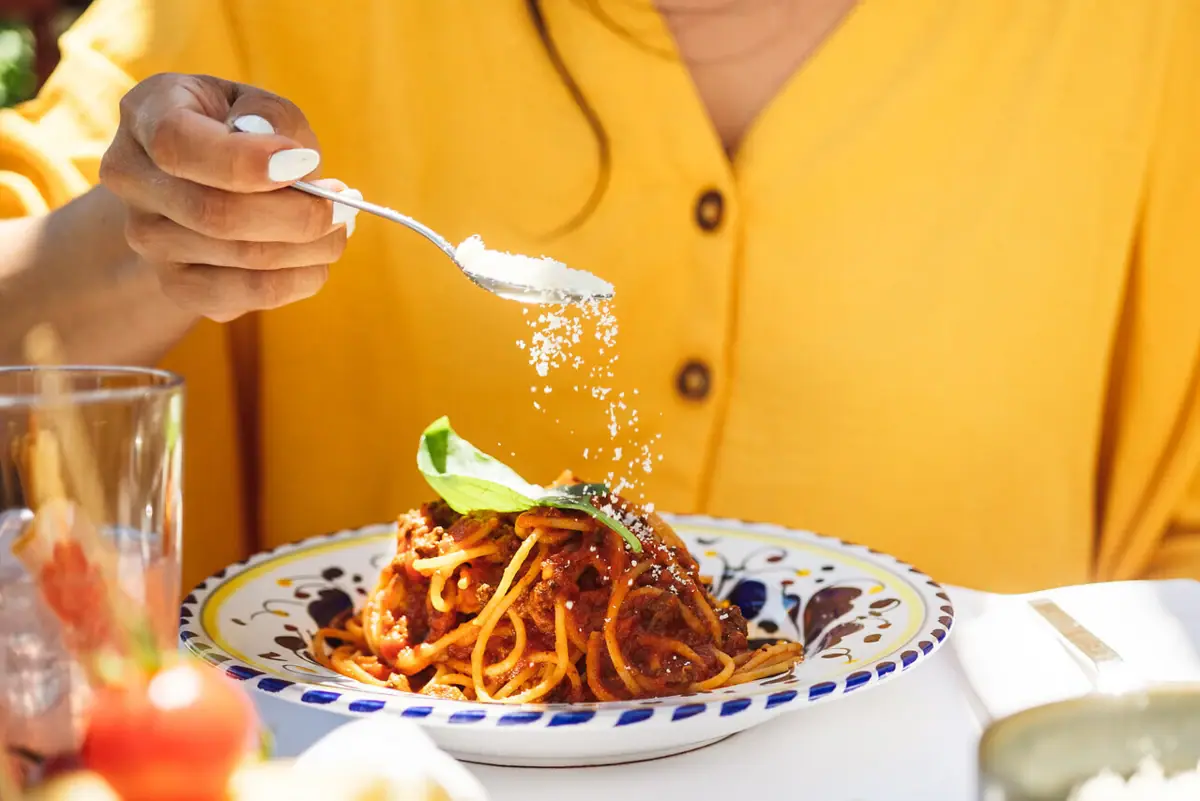 Ristorante all’A-ROSA Lago di Garda Una persona sta cospargendo del parmigiano su un piatto di spaghetti.