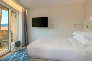 Zona notte Letto con TV a schermo piatto a parete in una stanza elegante.