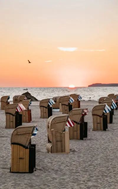 Gruppo di sedie su una spiaggia al tramonto.