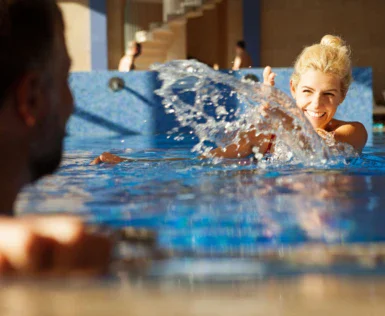 Donna che nuota in una piscina con schizzi d'acqua.