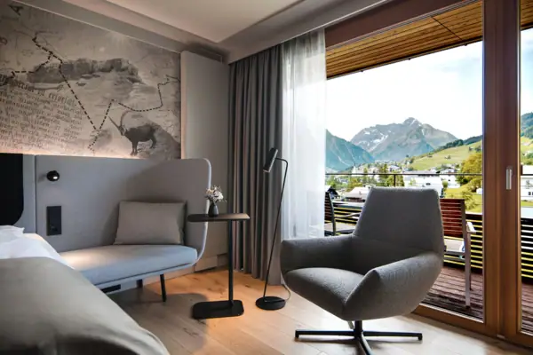 Ein modernes Hotelzimmer mit einem Sofa, einem Tisch und einem Stuhl.