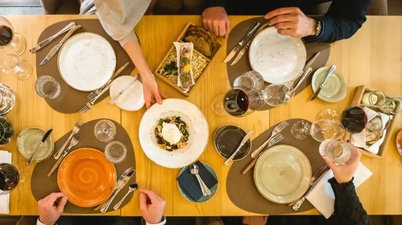 Gruppo di persone sedute a un tavolo apparecchiato con piatti e posate.