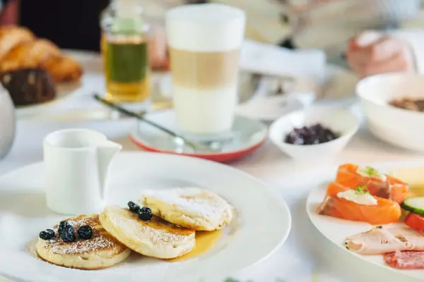 Un piatto di pancake, guarnito con mirtilli e zucchero a velo.