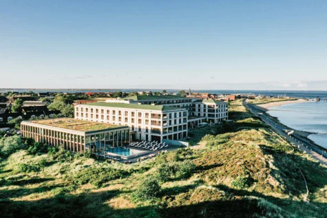 Edificio con piscina circondato da un paesaggio naturale, con vista sull'oceano.