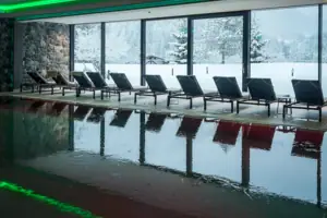 Una piscina con delle sedie davanti a una grande finestra.