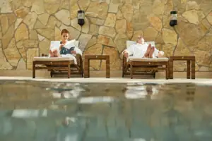 Un uomo e una donna sono seduti su delle sdraio a bordo piscina.