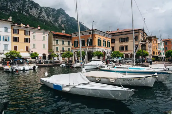 Gargnano Barche nel porto con edifici e montagne sullo sfondo, sul Lago di Garda.