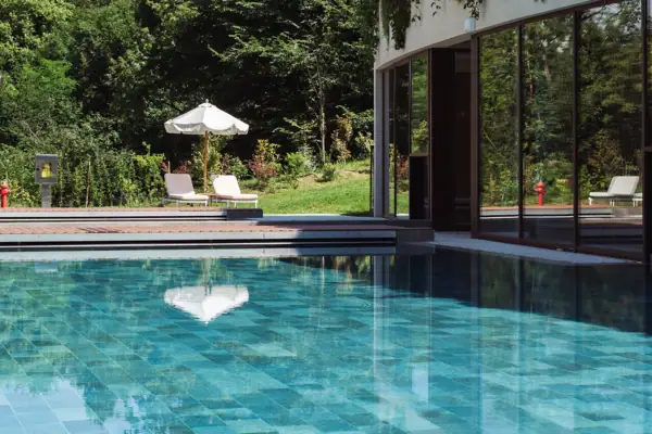 Piscina all'aperto con piante accanto a un edificio.