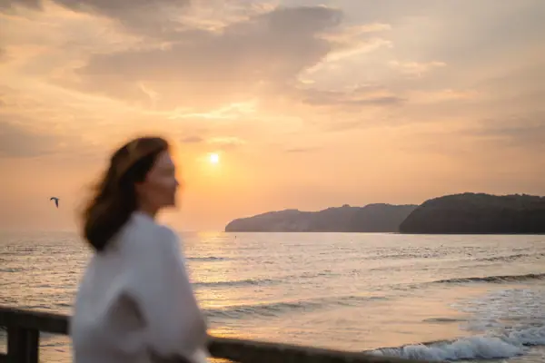 Una donna è in piedi sulla spiaggia.