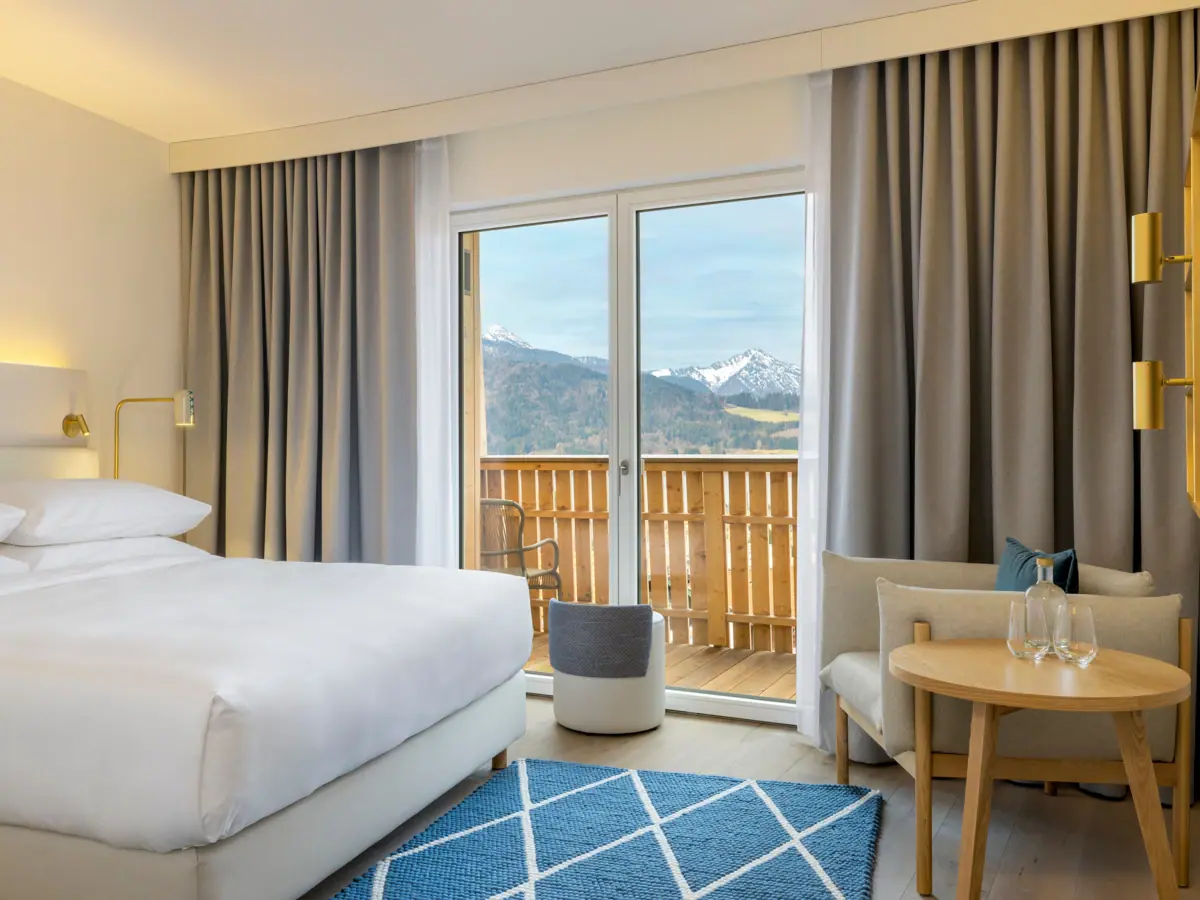 Camera d'albergo con letto, tappeto e poltrona.