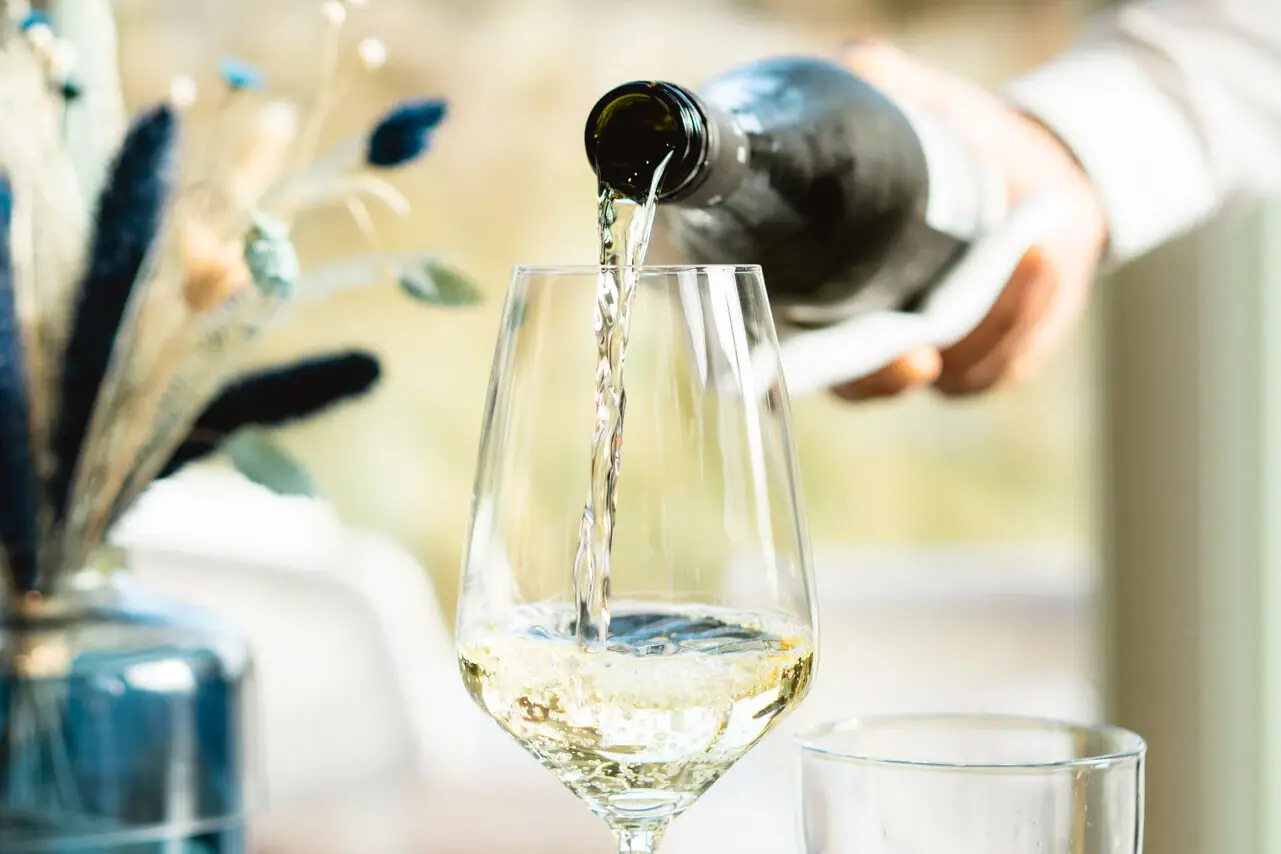 Eine Person gießt Wein in ein Glas.