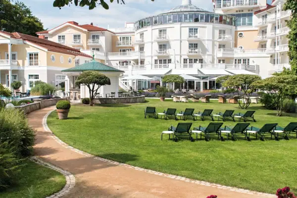 Sedia a sdraio in giardino con alberi e cielo sereno sullo sfondo.