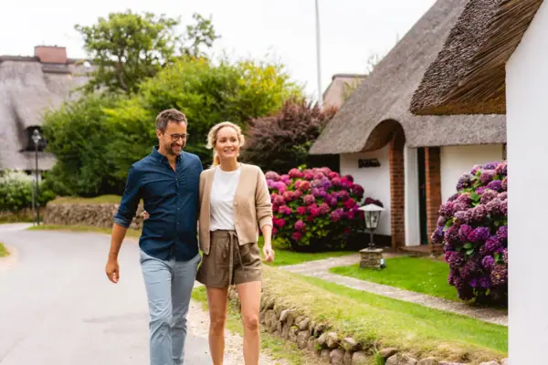 Un uomo e una donna passeggiano per una strada di Kampen, sull’isola di Sylt.