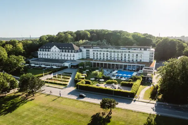 Ein großes weißes Gebäude mit Bäumen und einer Straße.