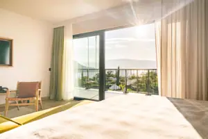Ein Zimmer mit einem Bett und einem Balkon mit Blick auf das Meer.
