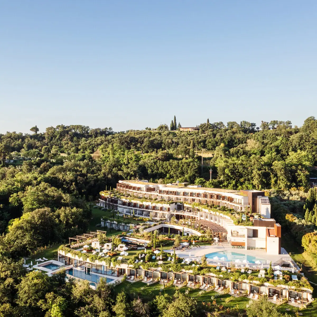 Das A-ROSA Gardasee Hotel Das Gebäude des A-ROSA Gardasee aus der Luft aufgenommen. Man erkennt die treppenförmige Bauweise und den weitläufigen Garten Außerdem sieht man die Pools auf den verschiedenen Ebenen.