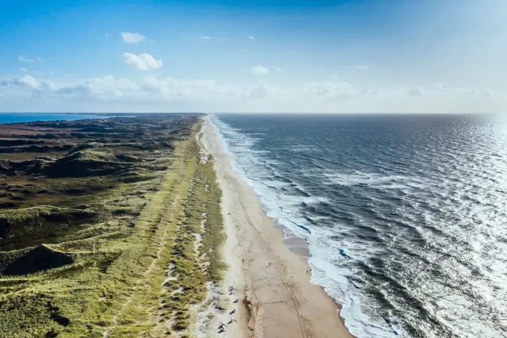 Lunga spiaggia con onde che lambiscono la riva.