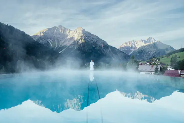 Persona a bordo piscina con un paesaggio montano sullo sfondo