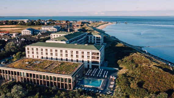 Vista aerea di un edificio con piscina e spiaggia sullo sfondo.