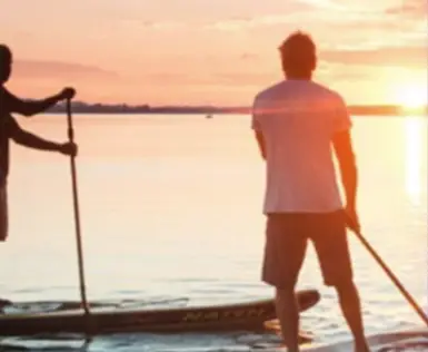 Un uomo su una tavola da paddle con una pagaia nell'acqua.