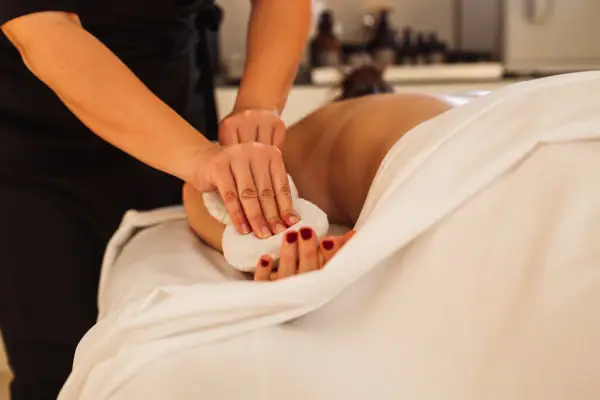 Eine Frau liegt in einem Bett mit einem Handtuch in der Hand.