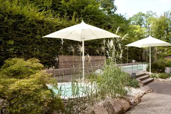 Weiße Sonnenschirme neben einem Pool im Freien