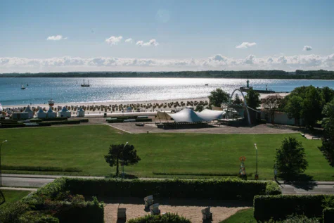 Ampio prato con un grande lago circondato da alberi e un cielo nuvoloso.