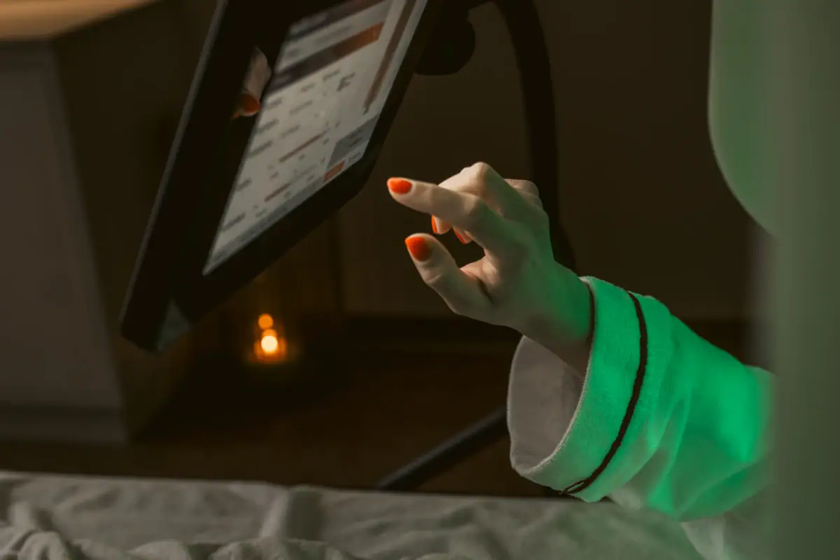 Eine Person im Bademantel betrachtet ein Tablet.