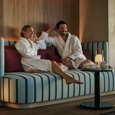 Una donna e un uomo siedono in accappatoio in un'accogliente area salotto della Day SPA del Grand Hotel Straubing.