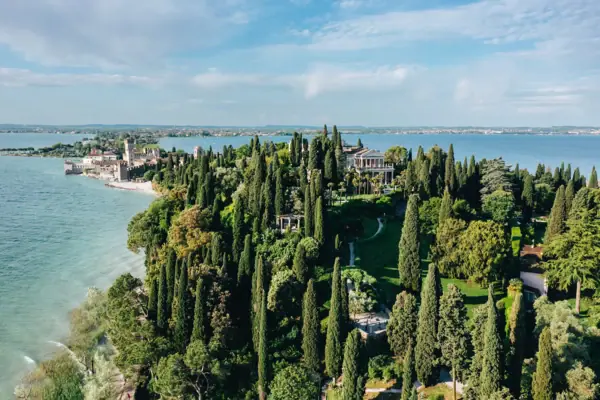 Punta San Vigilio Grande isola verde con alberi e un edificio in lontananza.