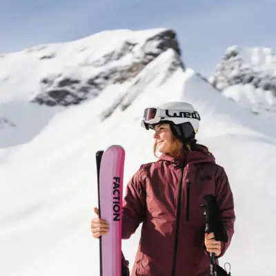 Donna con sci e bastoncini davanti a montagne innevate