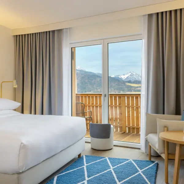 Camera d'albergo con letto, tappeto e poltrona.