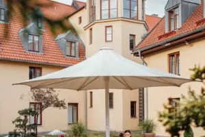 Una donna siede a un tavolo sotto un ombrellone nel cortile.