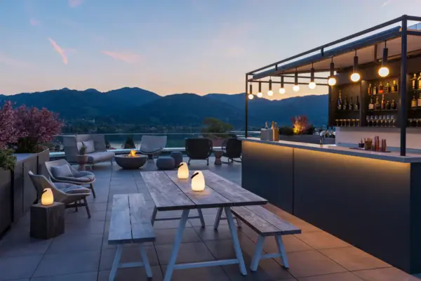 Terrazza con tavolo e sedie di fronte al lago, con un bar sullo sfondo.