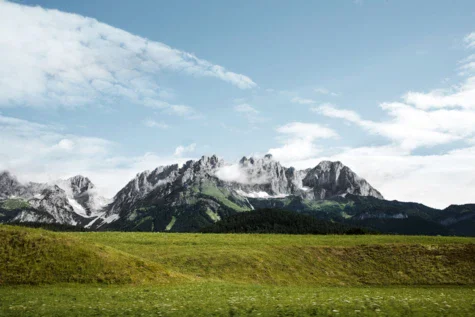 Un campo verde con montagne innevate sullo sfondo.