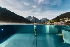 Una persona si trova in una piscina con le montagne sullo sfondo.